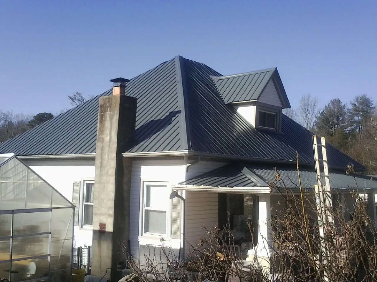 Dark blue standing seam metal roof on a white farmhouse with dormer — Slate & Tile Roof Repair by Roofing Brothers in Cincinnati