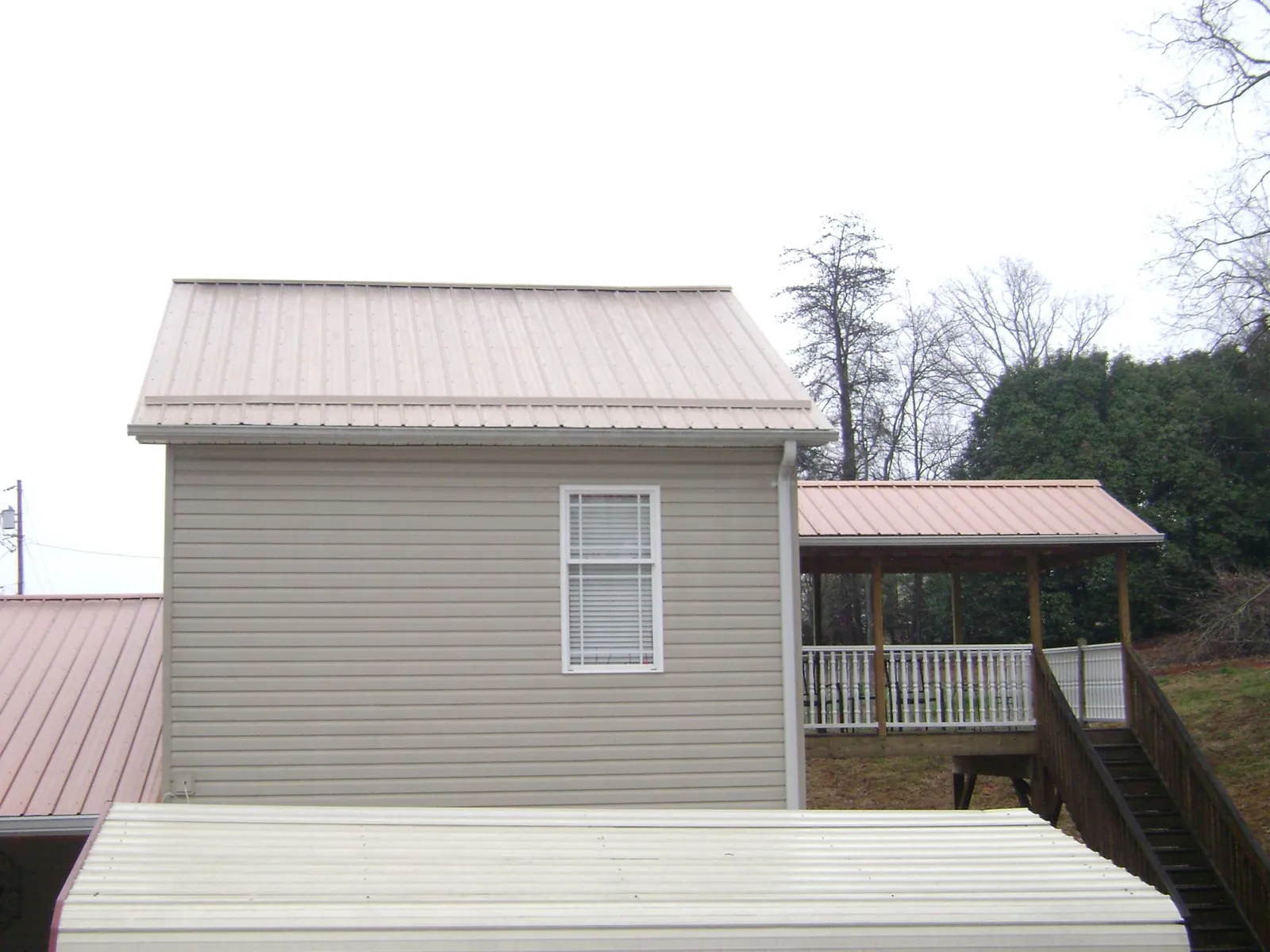 Tan metal roofs on a two story addition and attached porch, from a Roof Replacement job in Cincinnati